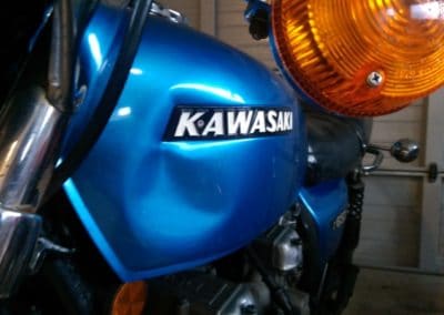 There is a closeup of a motorcycle shown. The brand name Kawasaki can clearly be seen on the side.