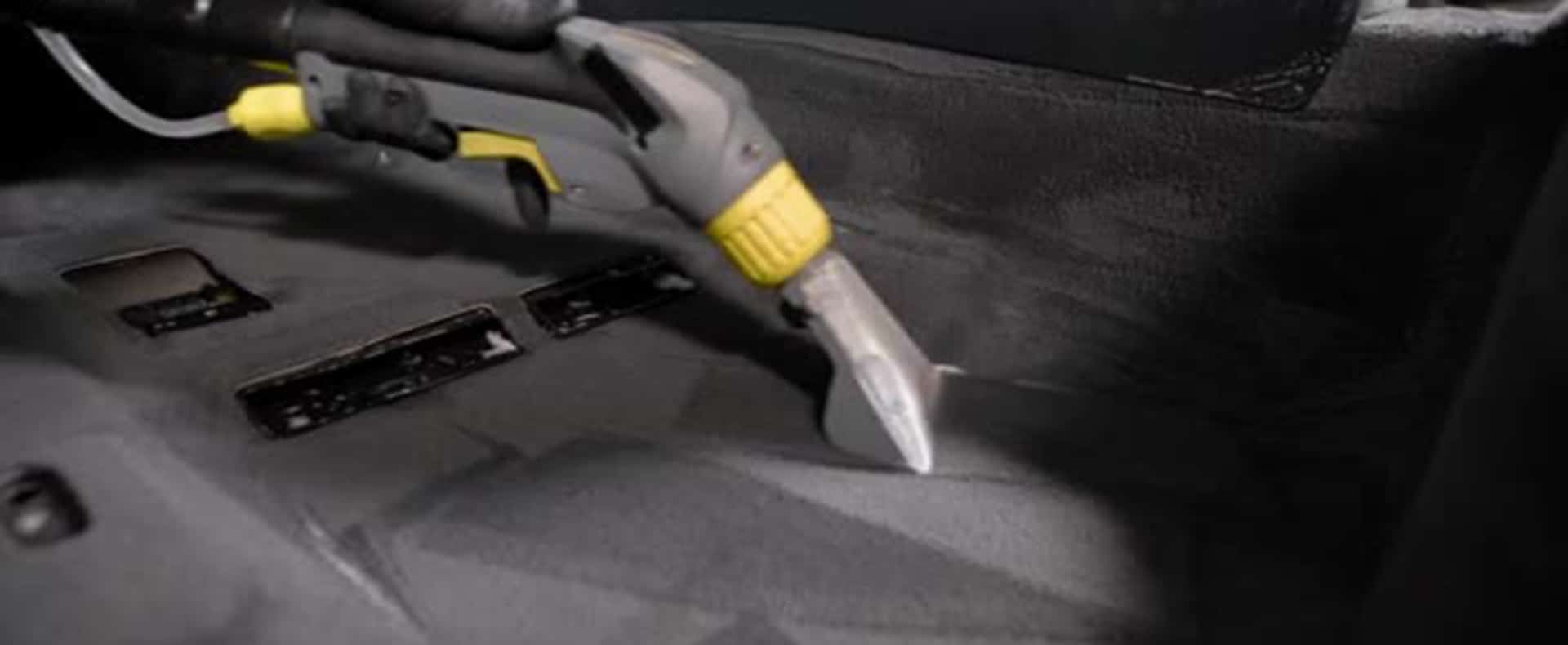 There's a piece of equipment shown on a car floor, actively cleaning the carpet and removing stains.