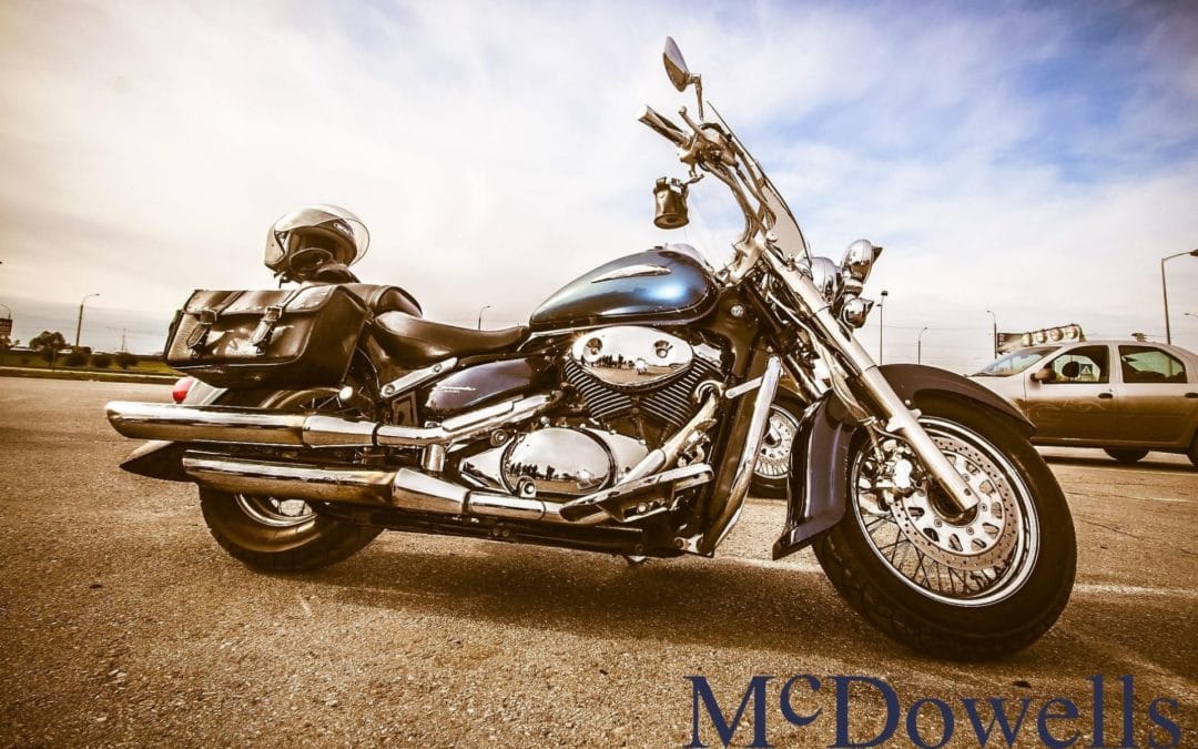 A blue and chrome motorcycle is parked in a lot with an open summer sky in the background.