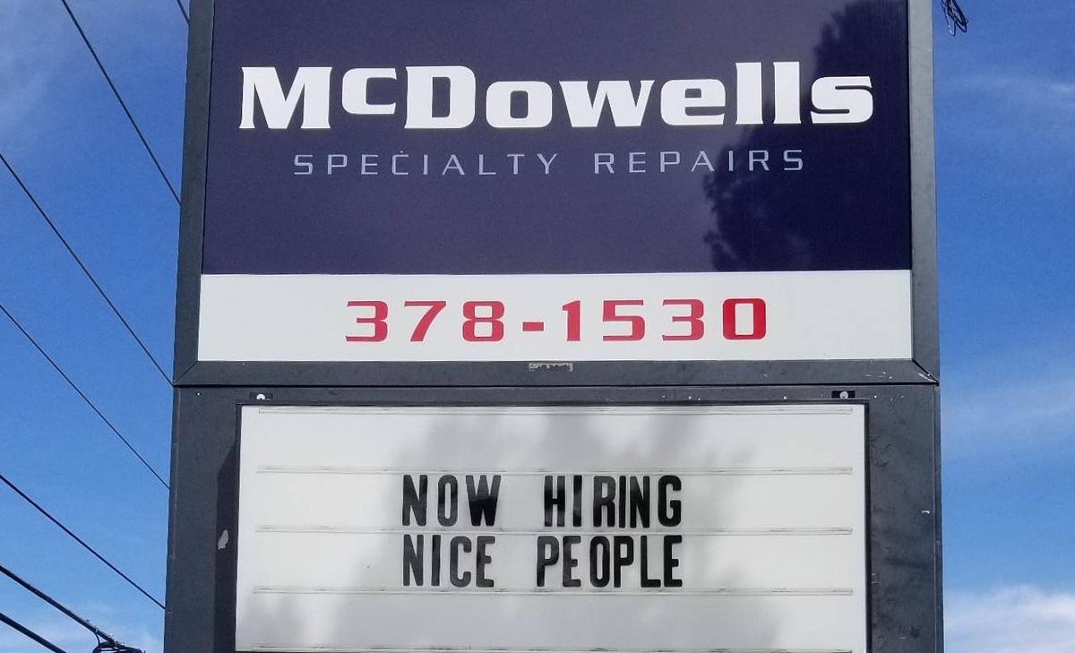 A sign for McDowells with their phone number. There's text below that says 'Now Hiring Nice People'.
