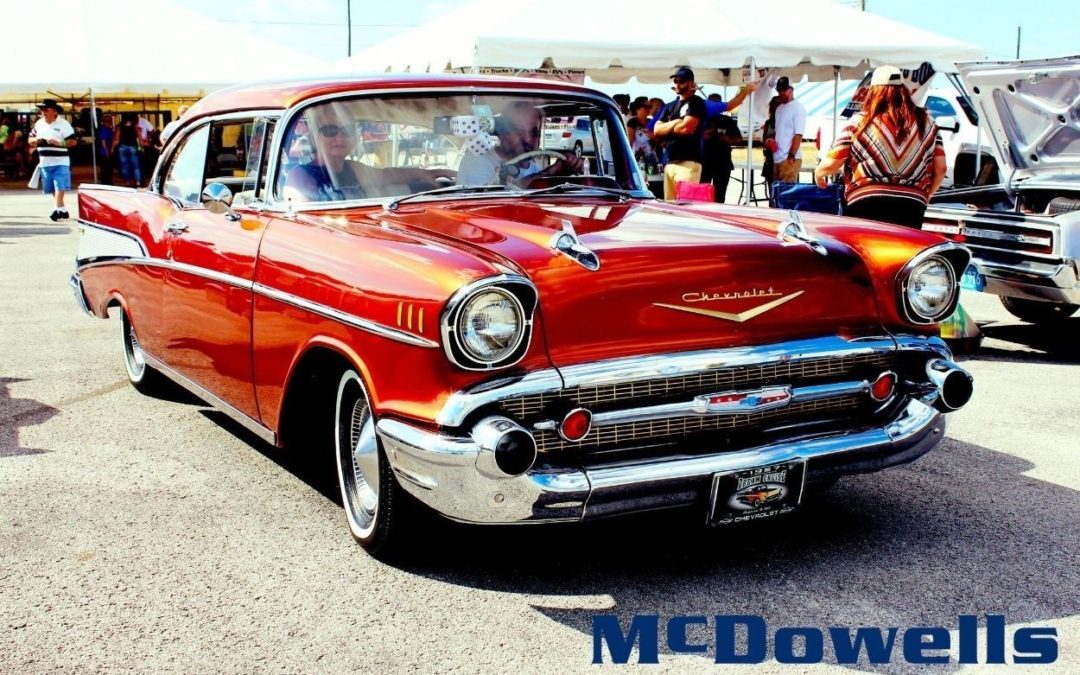 Old red Chevrolet driving through a car sho