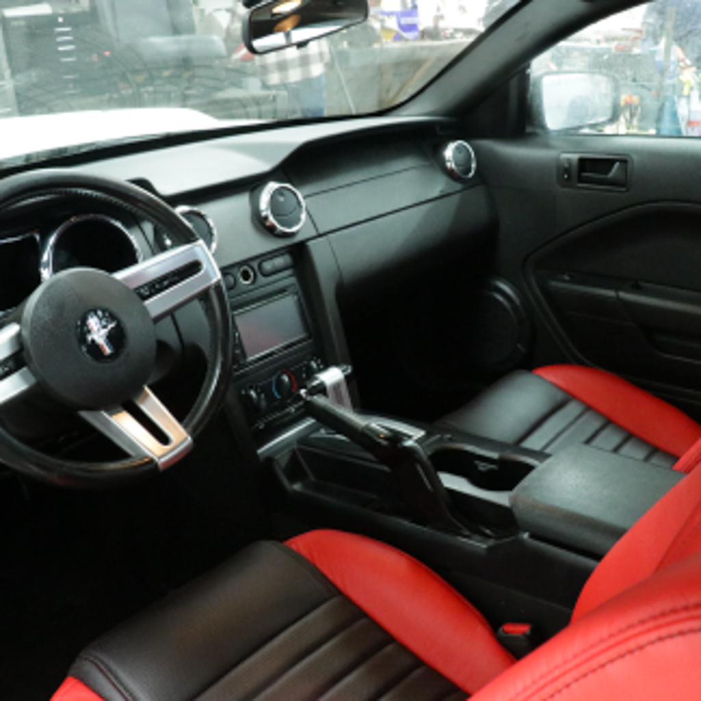 There is the interior of the front of a car. There is a lot of red, giving it a very fancy feeling.